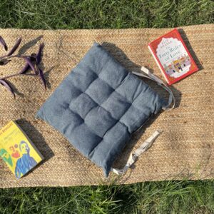 Upcycled chair pad made from repurposed fabrics placed on a mat with books – eco-friendly handmade cushion for sustainable home décor.