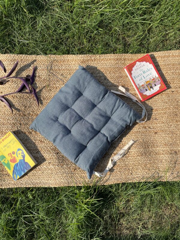 Upcycled chair pad made from repurposed fabrics placed on a mat with books – eco-friendly handmade cushion for sustainable home décor.
