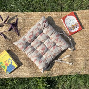 Upcycled chair pad made from repurposed fabrics placed on a mat with books – eco-friendly handmade cushion for sustainable home décor.