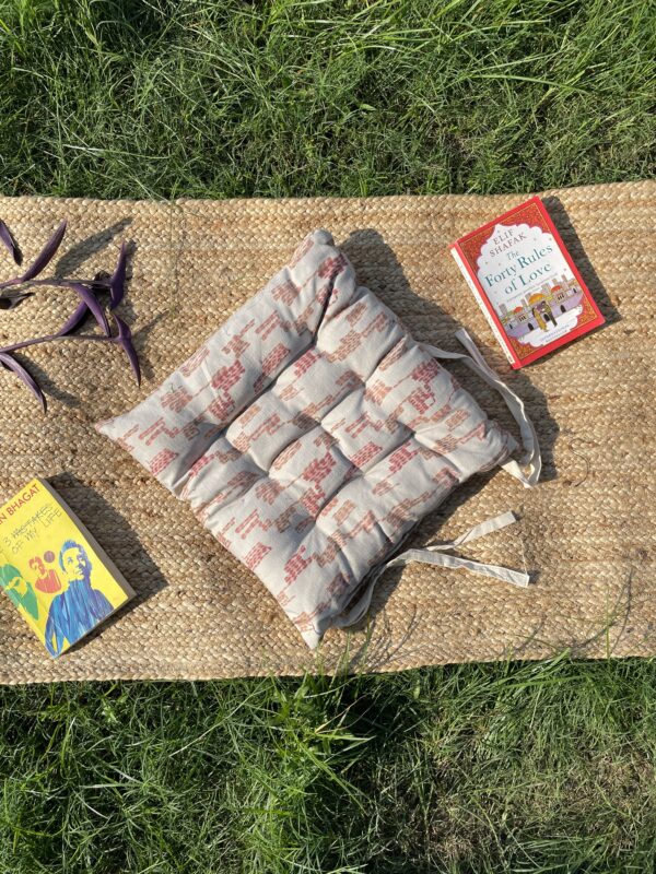 Upcycled chair pad made from repurposed fabrics placed on a mat with books – eco-friendly handmade cushion for sustainable home décor.