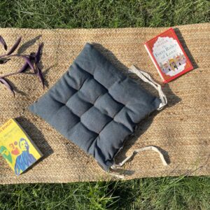Upcycled chair pad made from repurposed fabrics placed on a mat with books – eco-friendly handmade cushion for sustainable home décor.