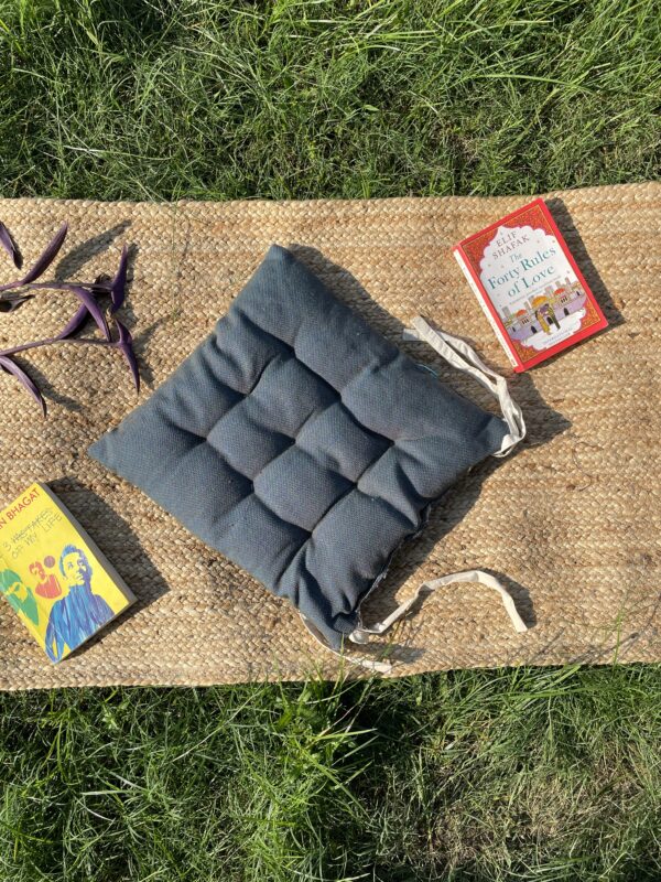 Upcycled chair pad made from repurposed fabrics placed on a mat with books – eco-friendly handmade cushion for sustainable home décor.