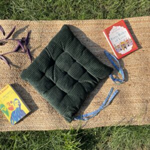Upcycled chair pad made from repurposed fabrics placed on a mat with books – eco-friendly handmade cushion for sustainable home décor.