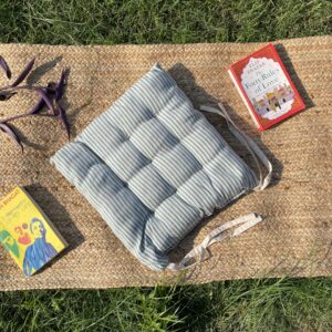 Upcycled chair pad made from repurposed fabrics placed on a mat with books – eco-friendly handmade cushion for sustainable home décor.