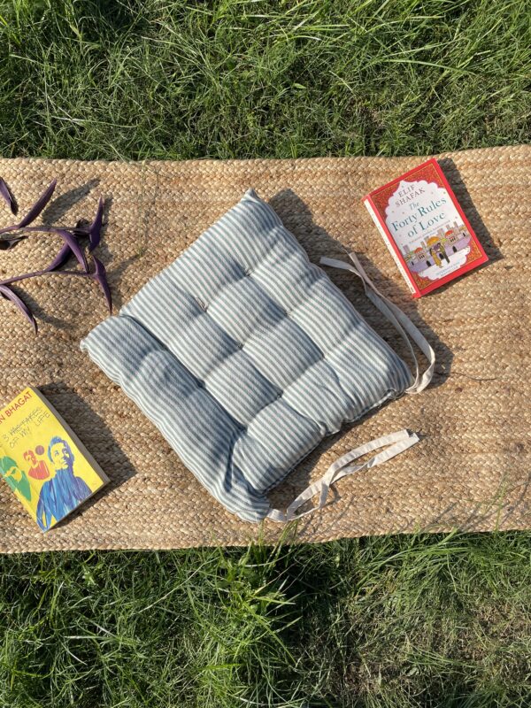 Upcycled chair pad made from repurposed fabrics placed on a mat with books – eco-friendly handmade cushion for sustainable home décor.