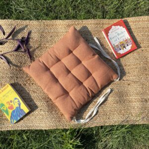 Upcycled chair pad made from repurposed fabrics placed on a mat with books – eco-friendly handmade cushion for sustainable home décor.