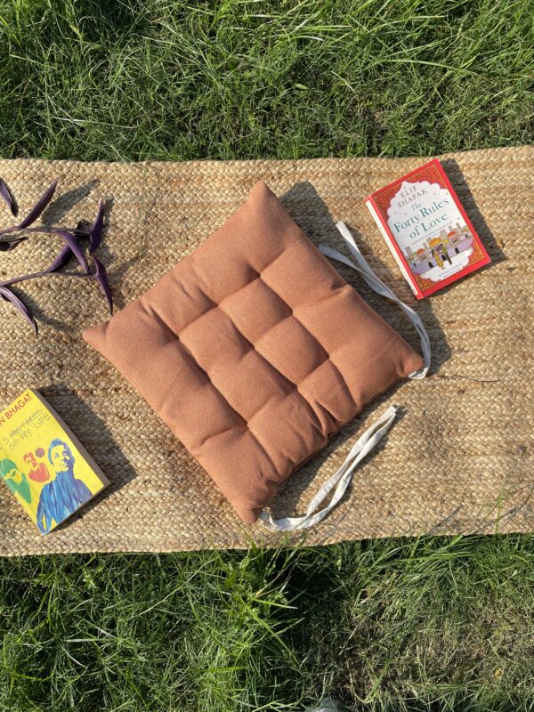 Upcycled chair pad made from repurposed fabrics placed on a mat with books – eco-friendly handmade cushion for sustainable home décor.