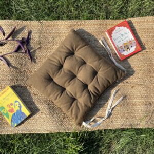 Upcycled chair pad made from repurposed fabrics placed on a mat with books – eco-friendly handmade cushion for sustainable home décor.