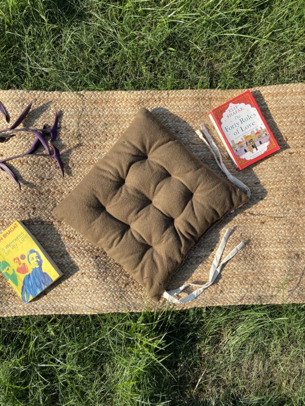 Upcycled chair pad made from repurposed fabrics placed on a mat with books – eco-friendly handmade cushion for sustainable home décor.