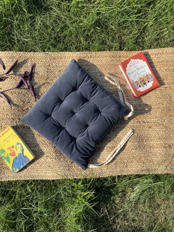 Upcycled chair pad made from repurposed fabrics placed on a mat with books – eco-friendly handmade cushion for sustainable home décor.
