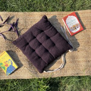 Upcycled chair pad made from repurposed fabrics placed on a mat with books – eco-friendly handmade cushion for sustainable home décor.