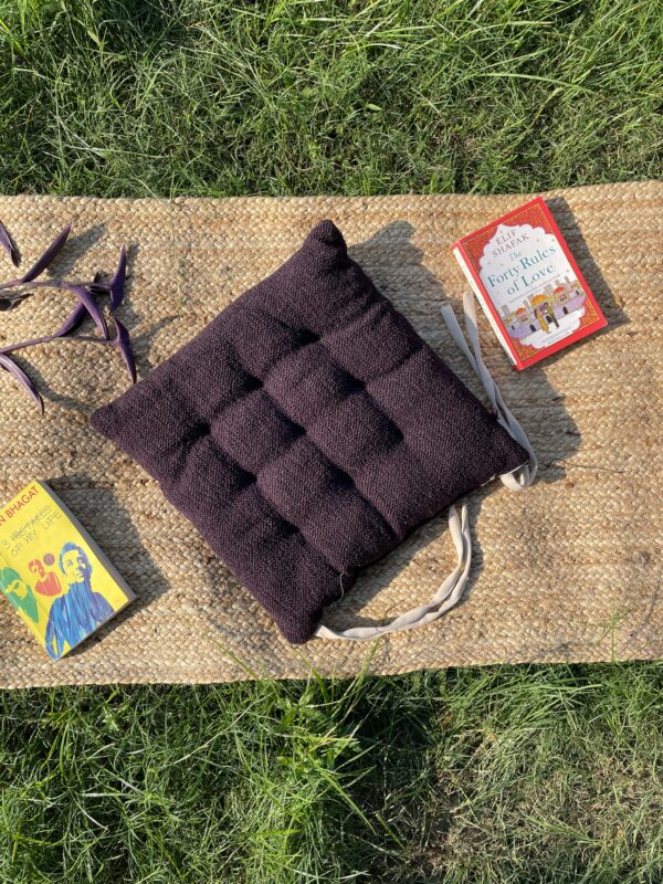 Upcycled chair pad made from repurposed fabrics placed on a mat with books – eco-friendly handmade cushion for sustainable home décor.