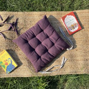 Upcycled chair pad made from repurposed fabrics placed on a mat with books – eco-friendly handmade cushion for sustainable home décor.