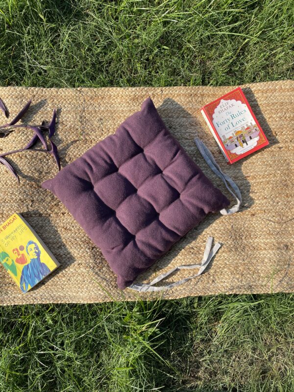 Upcycled chair pad made from repurposed fabrics placed on a mat with books – eco-friendly handmade cushion for sustainable home décor.