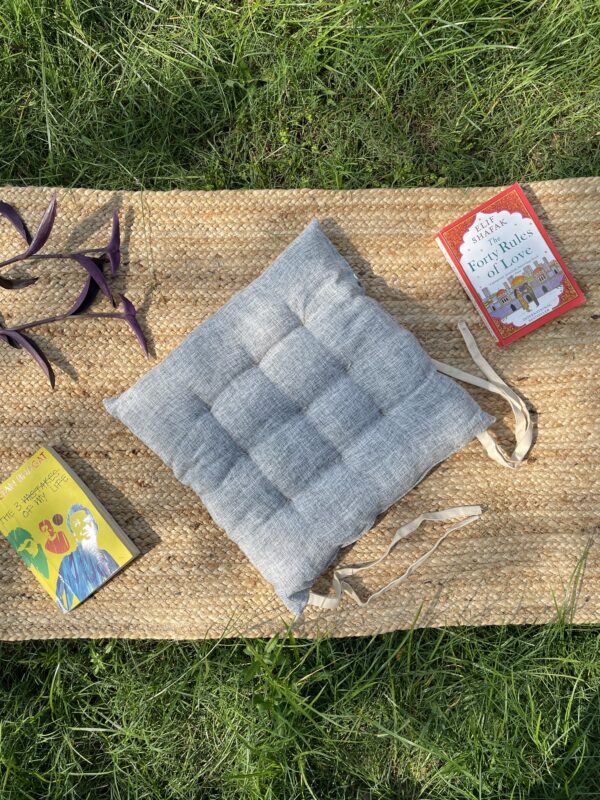 Upcycled chair pad made from repurposed fabrics placed on a mat with books – eco-friendly handmade cushion for sustainable home décor.
