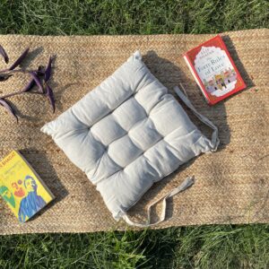 Upcycled chair pad made from repurposed fabrics placed on a mat with books – eco-friendly handmade cushion for sustainable home décor.