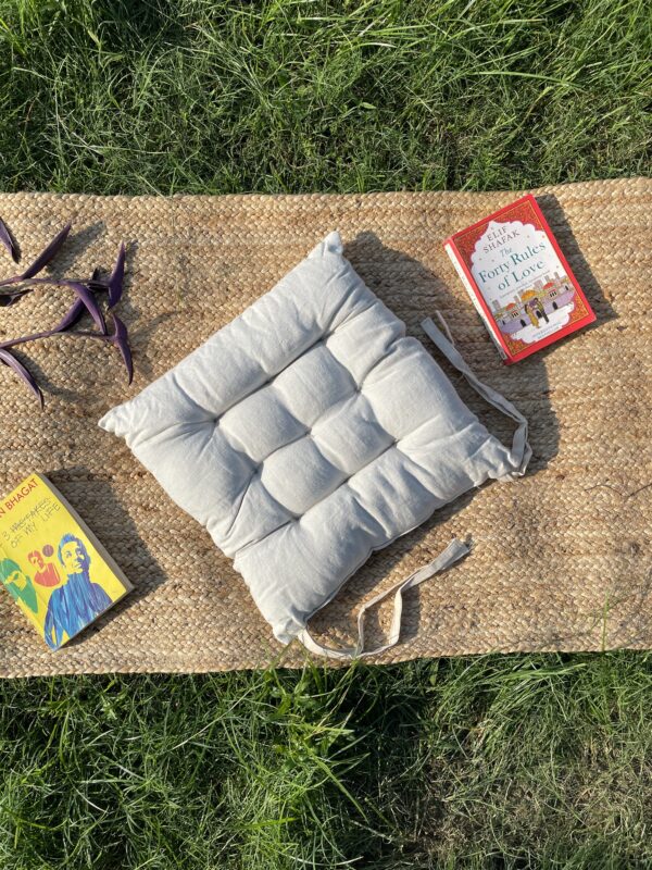 Upcycled chair pad made from repurposed fabrics placed on a mat with books – eco-friendly handmade cushion for sustainable home décor.