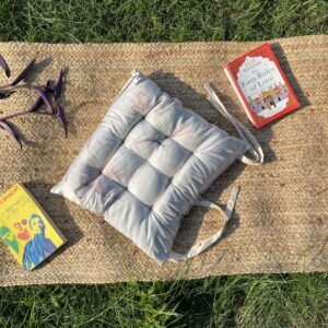 Upcycled chair pad made from repurposed fabrics placed on a mat with books – eco-friendly handmade cushion for sustainable home décor.