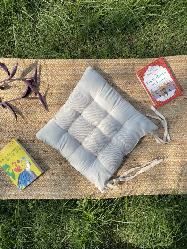 Upcycled chair pad made from repurposed fabrics placed on a mat with books – eco-friendly handmade cushion for sustainable home décor.