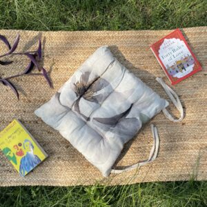Upcycled chair pad made from repurposed fabrics placed on a mat with books – eco-friendly handmade cushion for sustainable home décor.