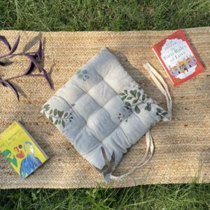Upcycled chair pad made from repurposed fabrics placed on a mat with books – eco-friendly handmade cushion for sustainable home décor.