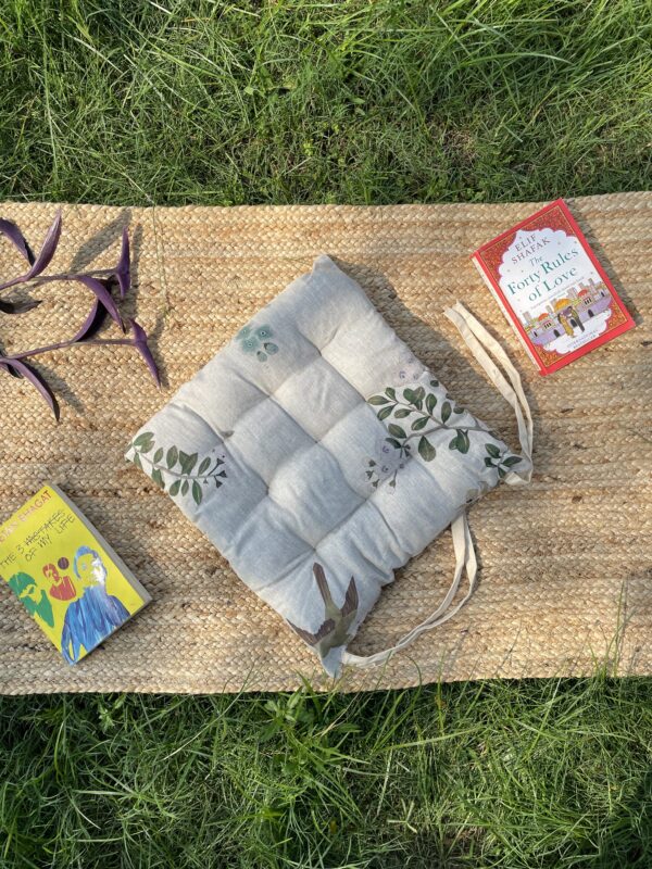 Upcycled chair pad made from repurposed fabrics placed on a mat with books – eco-friendly handmade cushion for sustainable home décor.