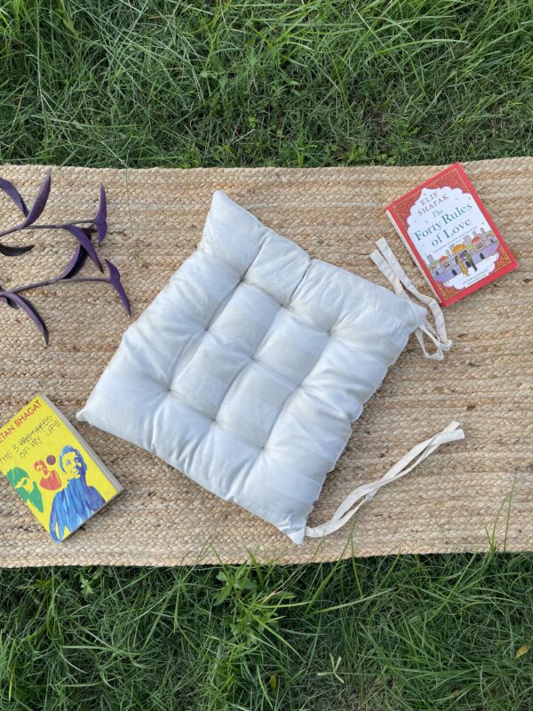 Upcycled chair pad made from repurposed fabrics placed on a mat with books – eco-friendly handmade cushion for sustainable home décor.