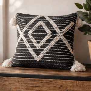 Sustainable designer cushion by Respun in black and ivory geometric weave, 18 x 18 inches with filler, styled on a rustic wooden console.