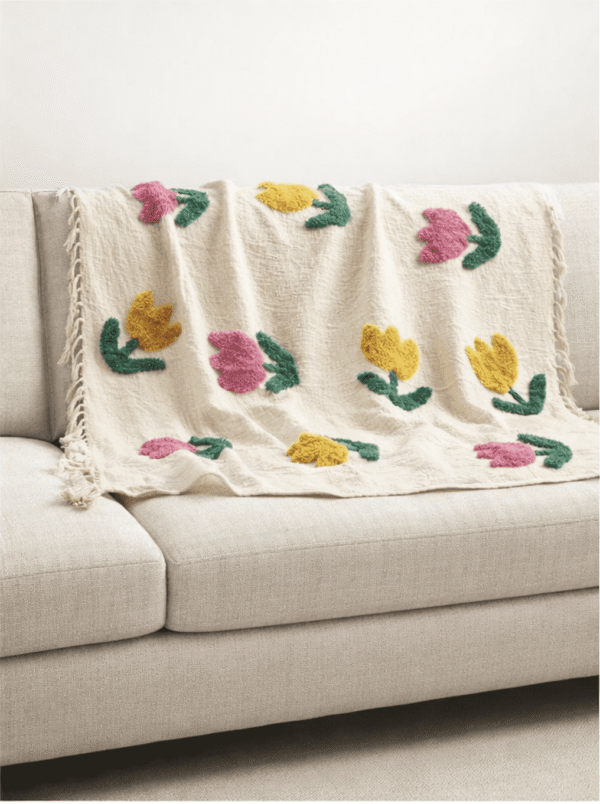 Ivory tufted cotton throw draped on a neutral sofa